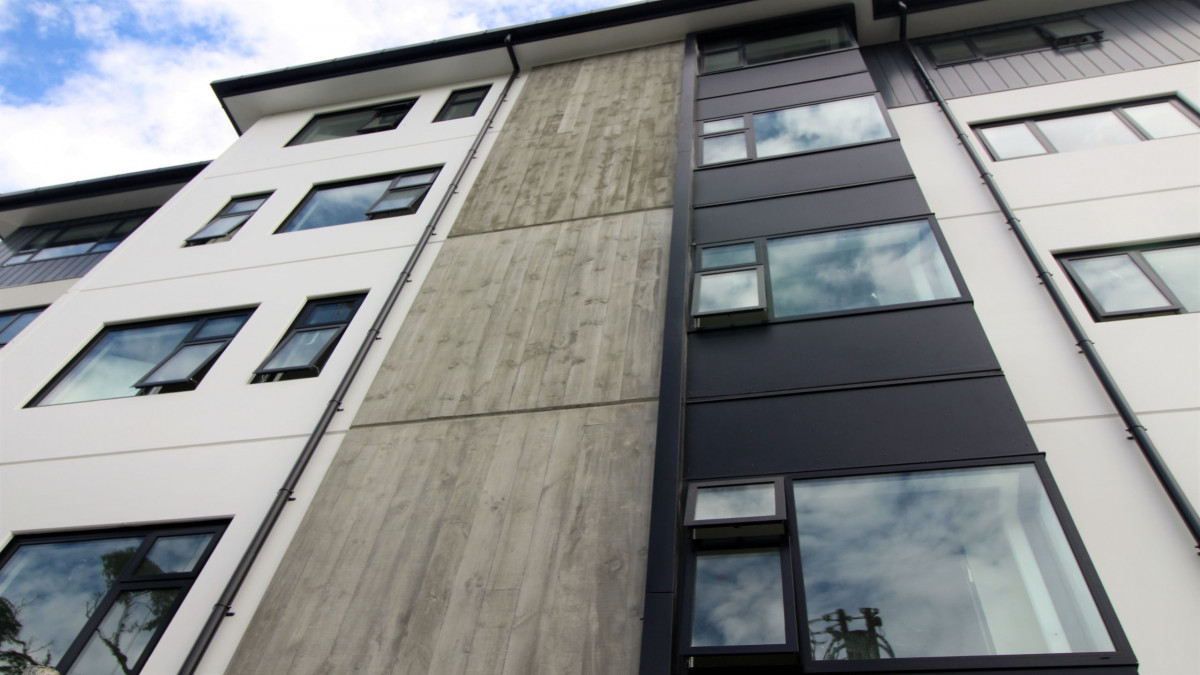 Vertical rough-sawn timber finish contrasts with timber panels and glass.